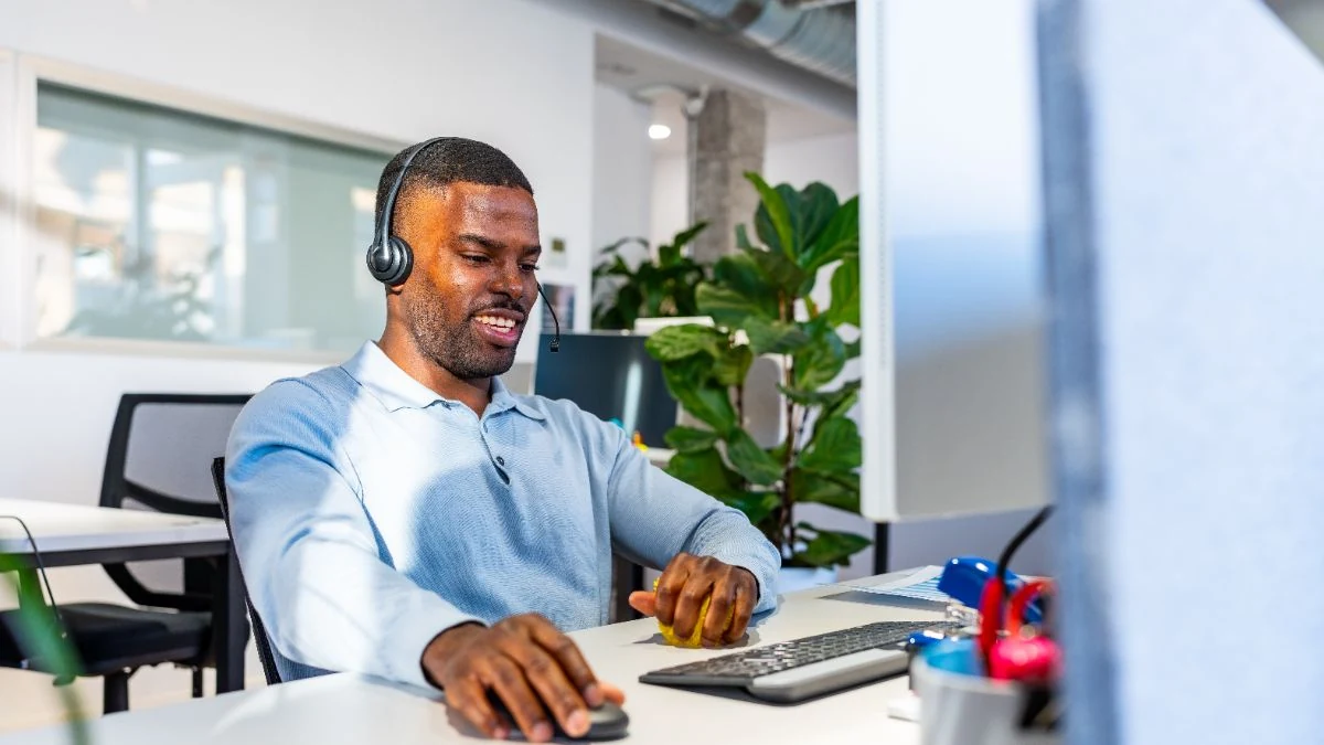 BDR on a headset making cold calls at his desk in a bright office
