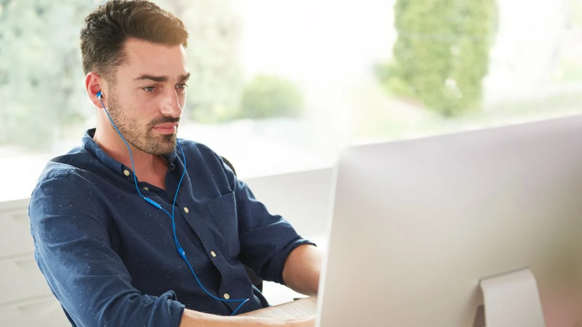 Sales rep with earphones practicing at his computer