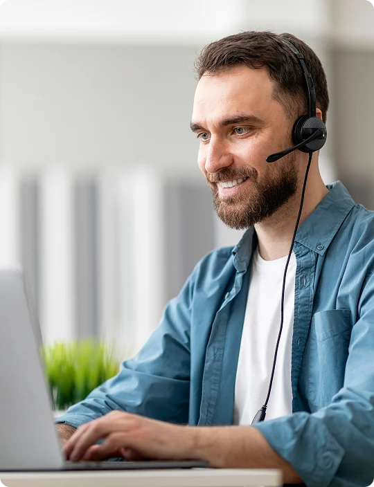 Insurance agent smiling on a call with a headset at a laptop