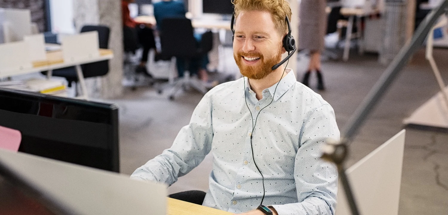 Sales manager coaching at a computer in an open office